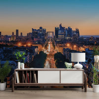Metropolis Dusk wallpaper mural of the glowing La Defense skyline at dusk above a wood sideboard in a living room