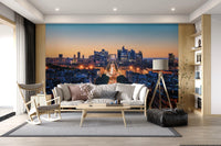 Metropolis Dusk wallpaper mural of a dusk skyline behind a beige sofa and wood rocking chair in a living room