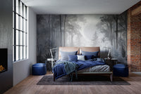 Misty Monochrome Forest wall mural in grey behind a blue bed and exposed brick wall in an industrial style bedroom