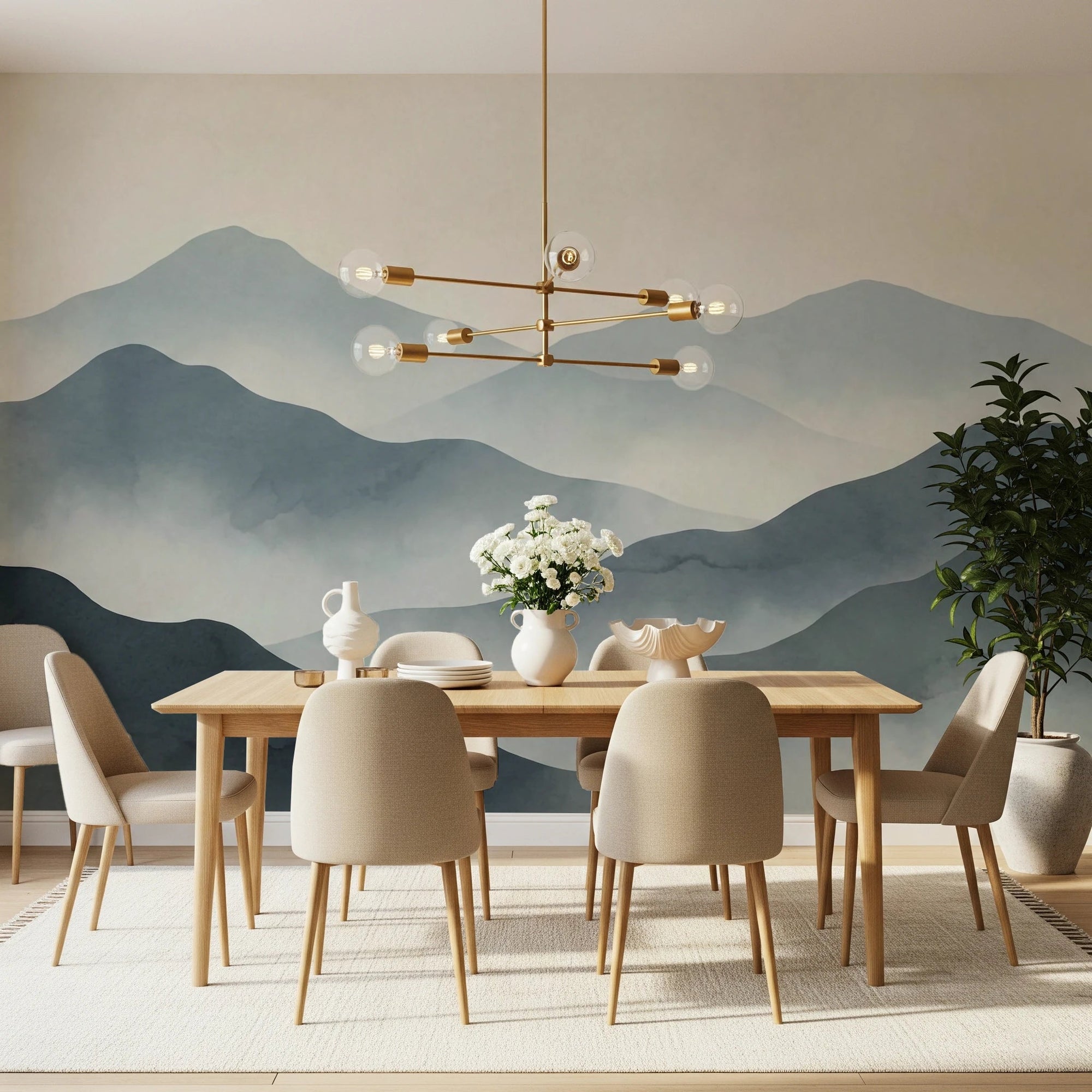 Misty Mountain Haze wallpaper mural of layered blue-gray mountains above a wood dining table with a brass chandelier