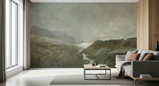 Misty Vale wallpaper mural, green valley with a stream on a wall beside a grey sofa in a sunlit living room
