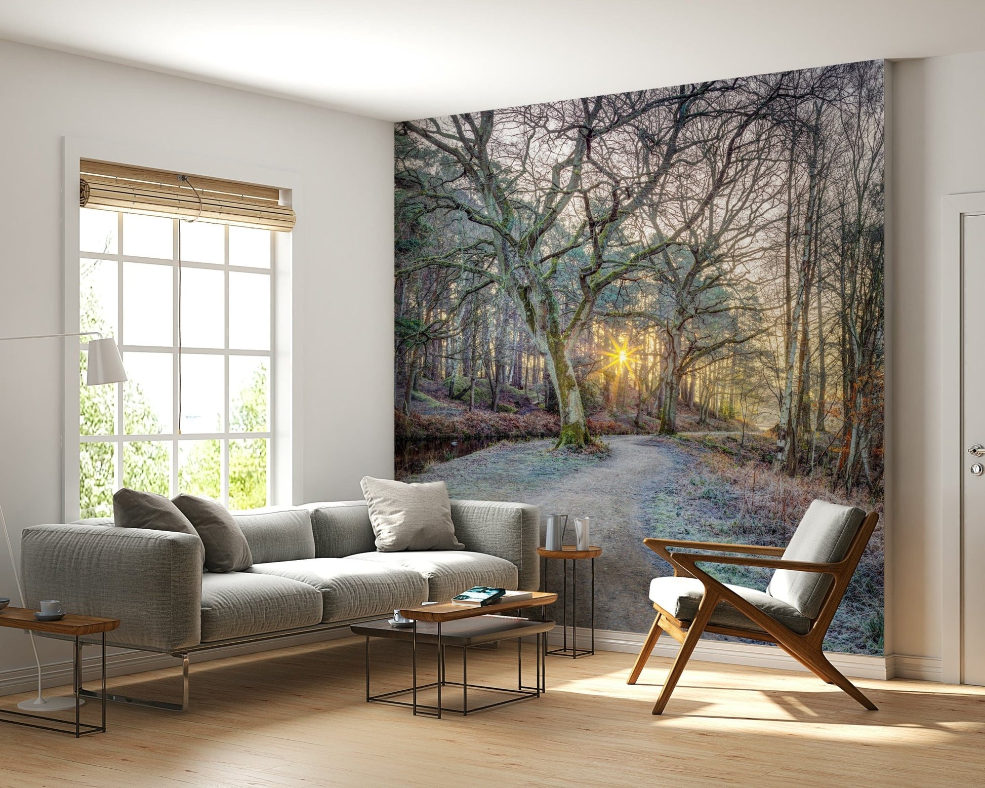 Misty Woodland Glare mural behind a grey sofa, wood accent chair and black nesting tables by a window