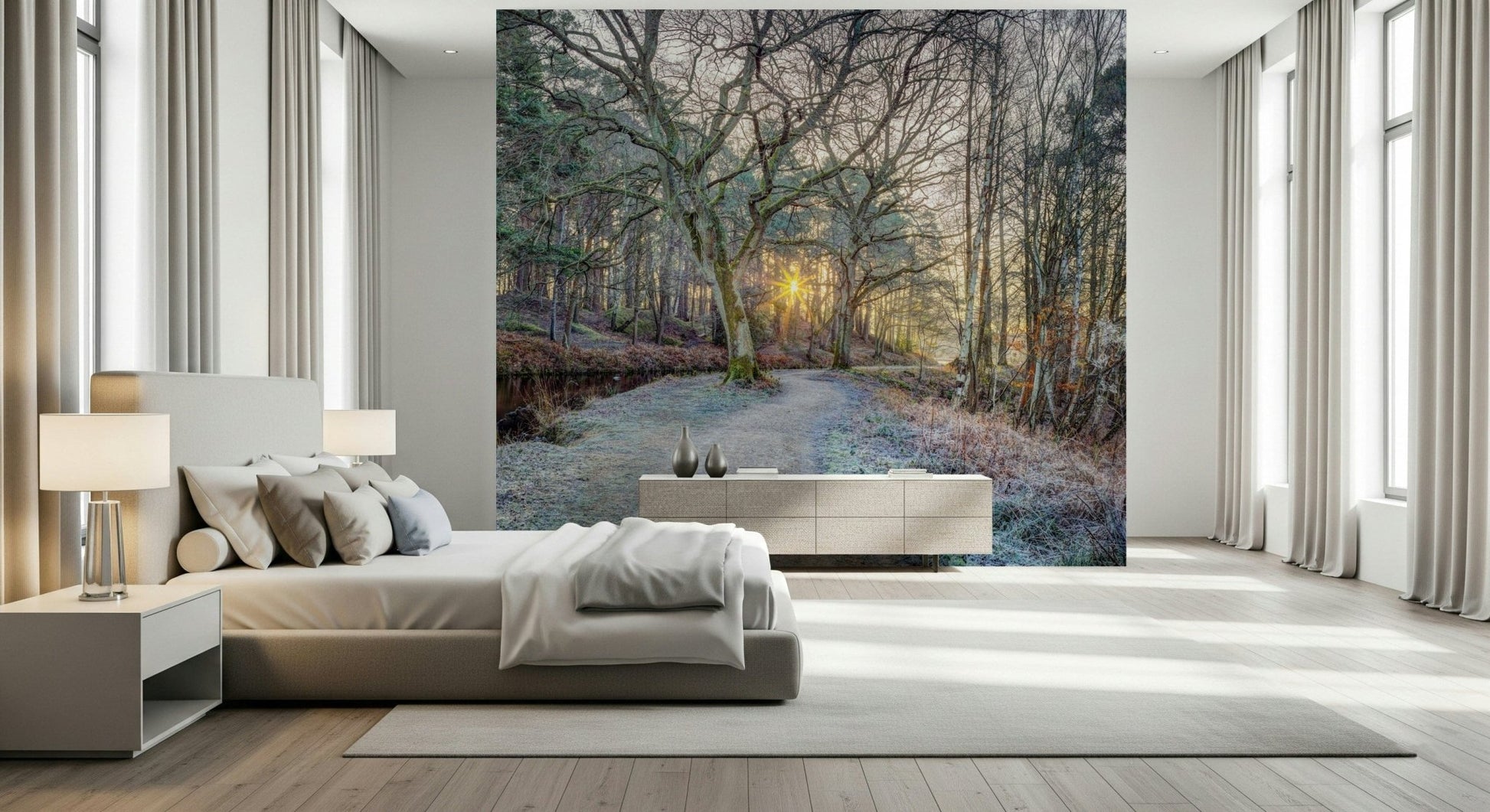 Misty Woodland Glare mural over a beige upholstered bed and long sideboard between tall curtained windows