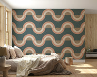 Modern Retro Arcs Decor wallpaper mural with teal and peach waves behind a beige bed and chunky knit throw in a bedroom