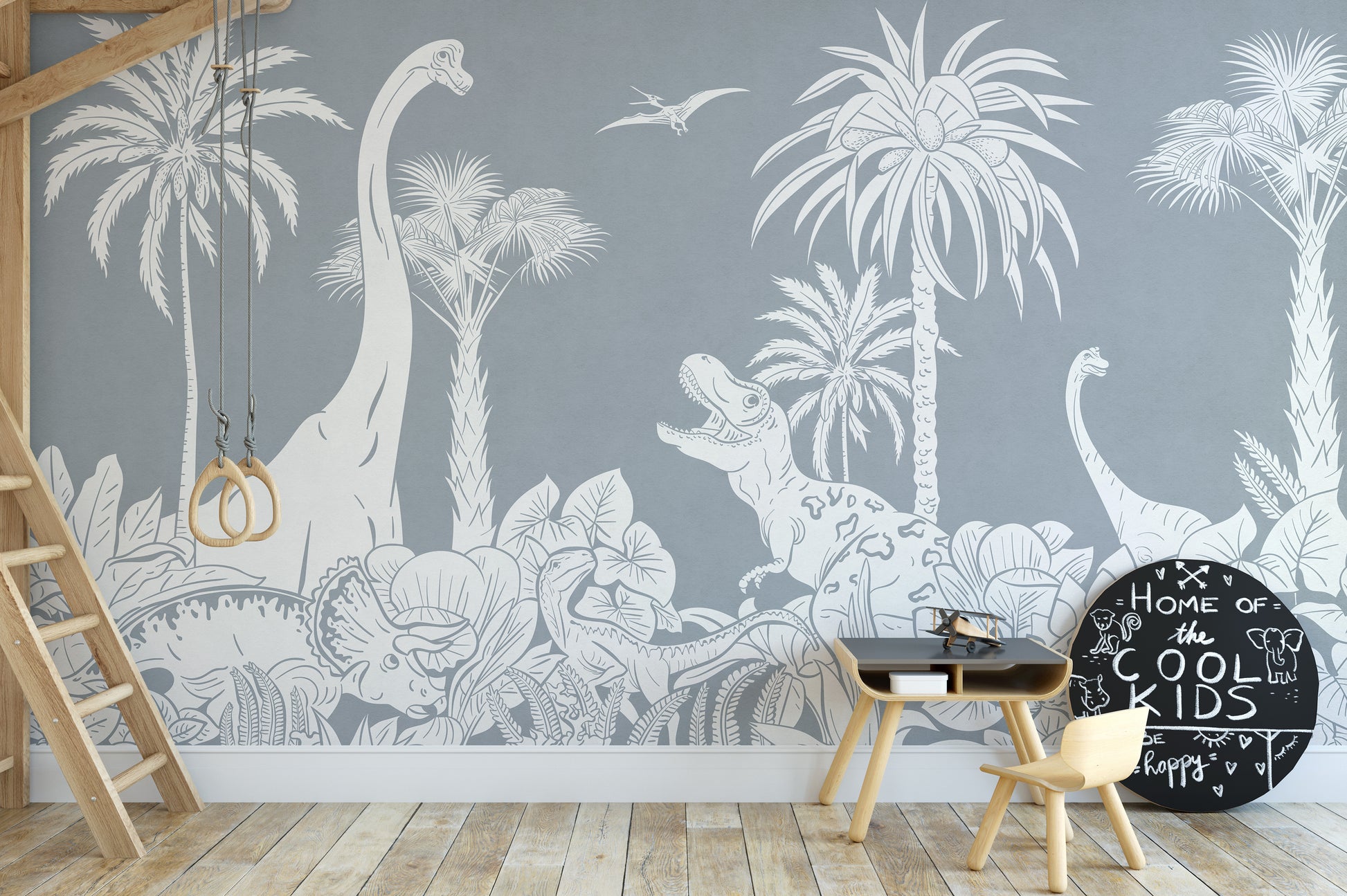 Monochrome Dino Blue wallpaper mural of grey dinosaur jungle behind a loft bed ladder, black table and chalkboard