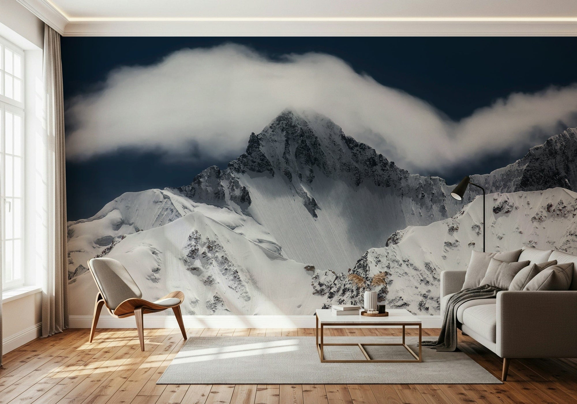Summit Cloudveil wallpaper mural of a cloud-wrapped snowy peak behind a cream sofa and wood chair in a living room