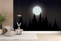 Mystical Moonlit Forest wallpaper with a bright moon and black pines behind a cream armchair in a living room