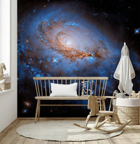 Nebula Dreams wall mural of a blue galaxy on black behind a wood spindle bench and rocking chair in a nursery