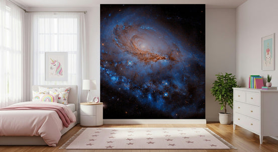 Nebula Dreams wall mural of a blue spiral galaxy on black space behind a pink bed with unicorn art in a girls bedroom