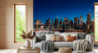Night Metropolis wallpaper mural of the blue night skyline above a grey sofa stacked with boho pillows in a living room