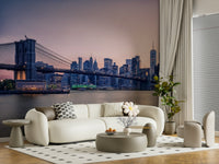 NYC Bridge at Dusk wallpaper mural of the twilight skyline behind a cream curved sofa and accent chair in a living room