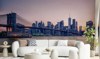 NYC Bridge at Dusk wallpaper mural of the Brooklyn Bridge and skyline at twilight behind a white bouclé sofa in a living room