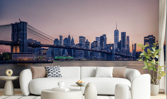 NYC Bridge at Dusk wallpaper mural of the Brooklyn Bridge and skyline at twilight behind a white bouclé sofa in a living room