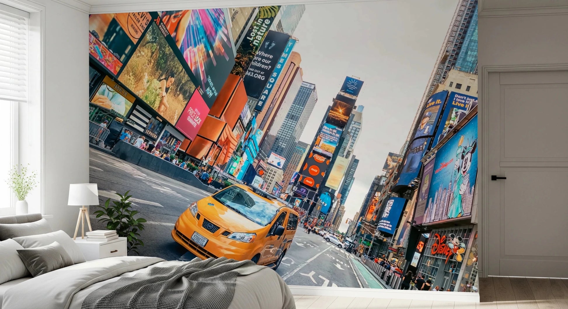 NYC Buzz wallpaper mural with a yellow taxi and bright billboards behind a grey bed and white nightstand in a bedroom