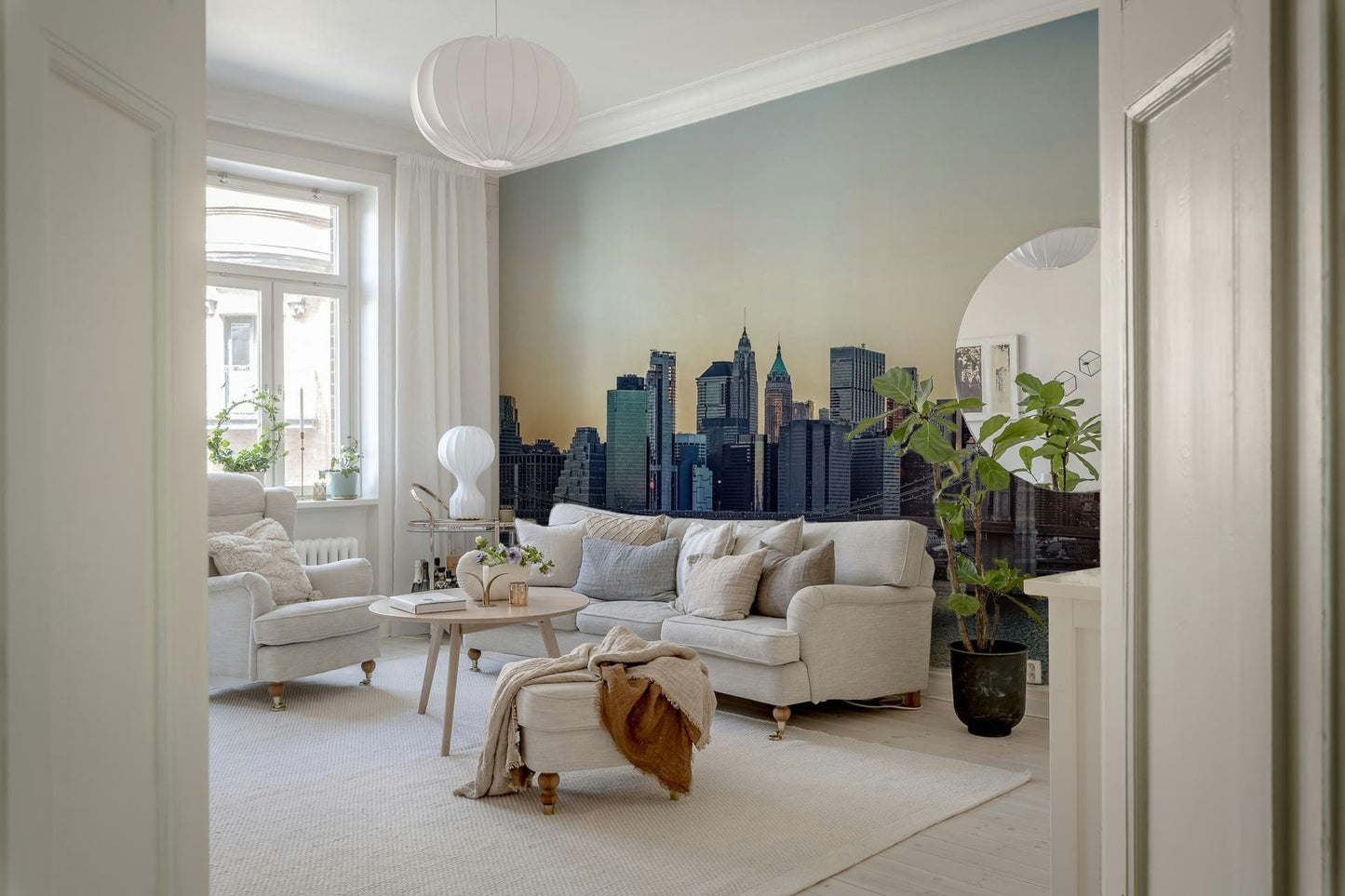 NYC Skyline at Dawn wallpaper mural of the hazy dawn skyline behind a cream sofa in a Scandinavian living room