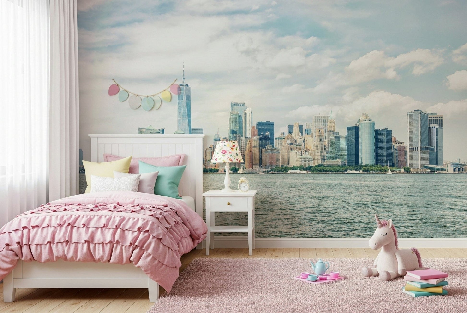 NYC Skyline View wallpaper mural of Manhattan across the water behind a pink bed and unicorn toy in a kids room