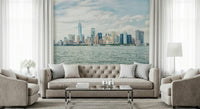 NYC Skyline View wallpaper mural of Manhattan across the harbor behind a beige tufted sofa and armchairs in a living room