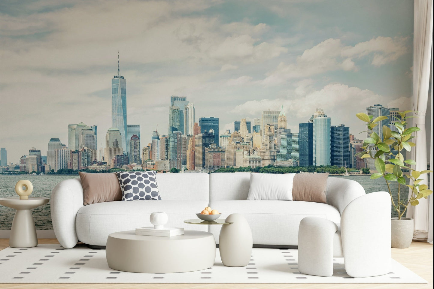 NYC Skyline View wallpaper mural of the cloudy daytime skyline behind a white curved sofa in a bright living room