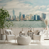 NYC Skyline View wallpaper mural of the harbor skyline behind white rattan armchairs and a woven table in a sunroom