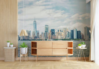 NYC Skyline View wallpaper mural of the daytime skyline above a wood sideboard and potted plants in a bright room