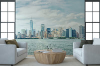 NYC Skyline View wallpaper mural of Lower Manhattan across the harbor between two white armchairs in a living room