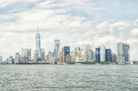 NYC Skyline View wallpaper mural shown as a full-wall view of Lower Manhattan across the harbor under a cloudy blue sky