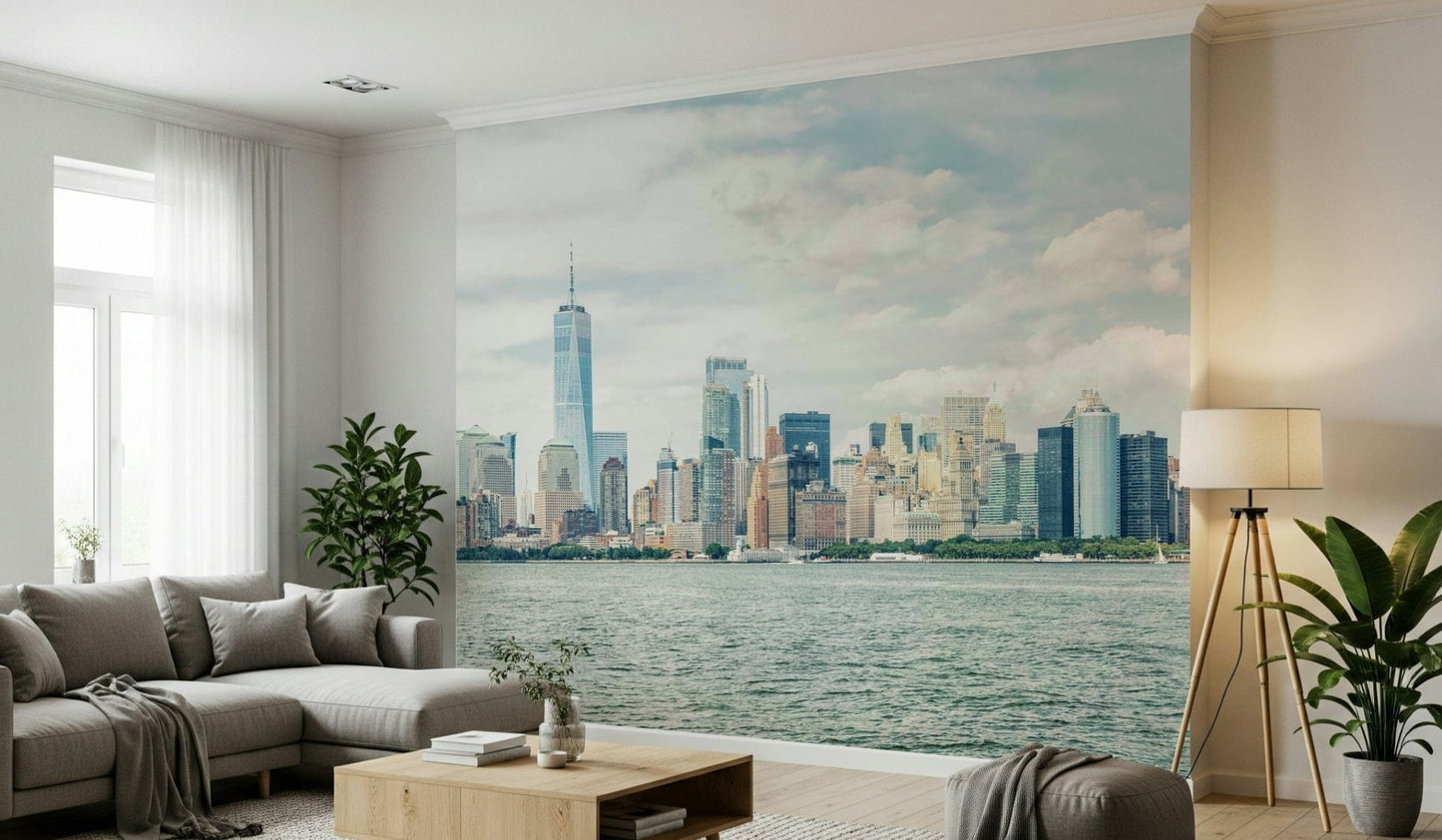 NYC Skyline View wallpaper mural of Manhattan across the water behind a grey sectional sofa in a living room