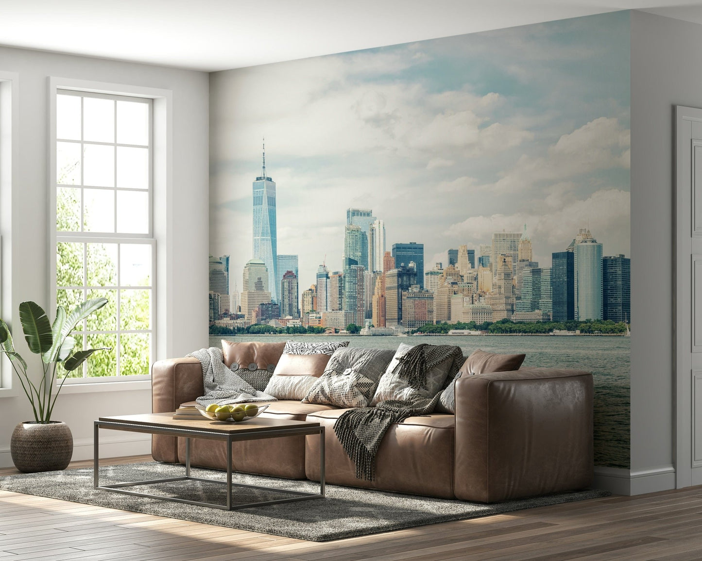 NYC Skyline View wallpaper mural of the daytime skyline behind a brown leather sectional sofa in a bright living room