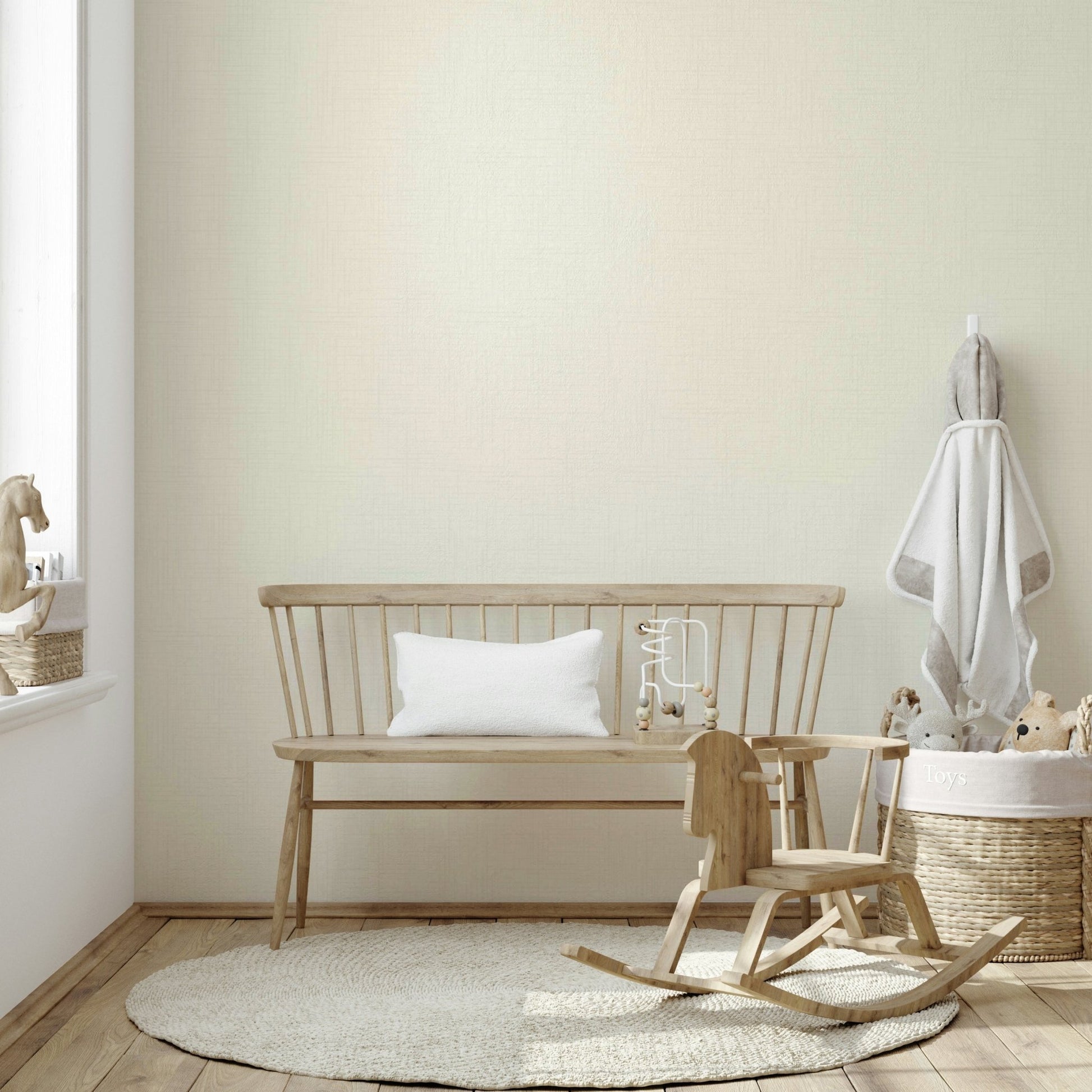 Old Canvas Cannoli Cream wallpaper in soft cream in a nursery with wooden bench, rocking horse and toy basket