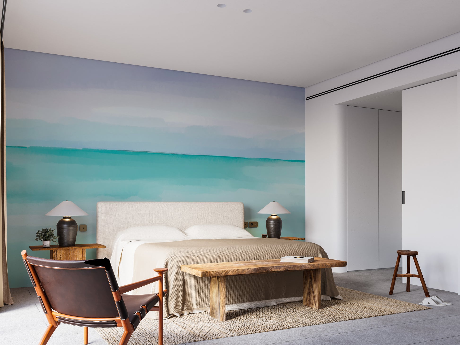 Turquoise Ocean wallpaper mural in a bedroom with a beige upholstered bed, table lamps and a live-edge wooden bench