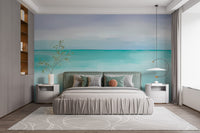 Turquoise Ocean wallpaper mural as a soft seascape headboard wall behind an upholstered bed and white nightstands