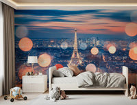 Parisian Lights wallpaper mural of the lit Eiffel Tower above a white bed and toys in a childs bedroom