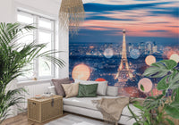 Parisian Lights wallpaper mural of the Eiffel Tower at twilight behind a grey daybed and plants in a living room