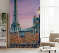 Parisian Twilight wallpaper mural of Eiffel Tower and pink sky beside a beige armchair and bookshelf in a living room