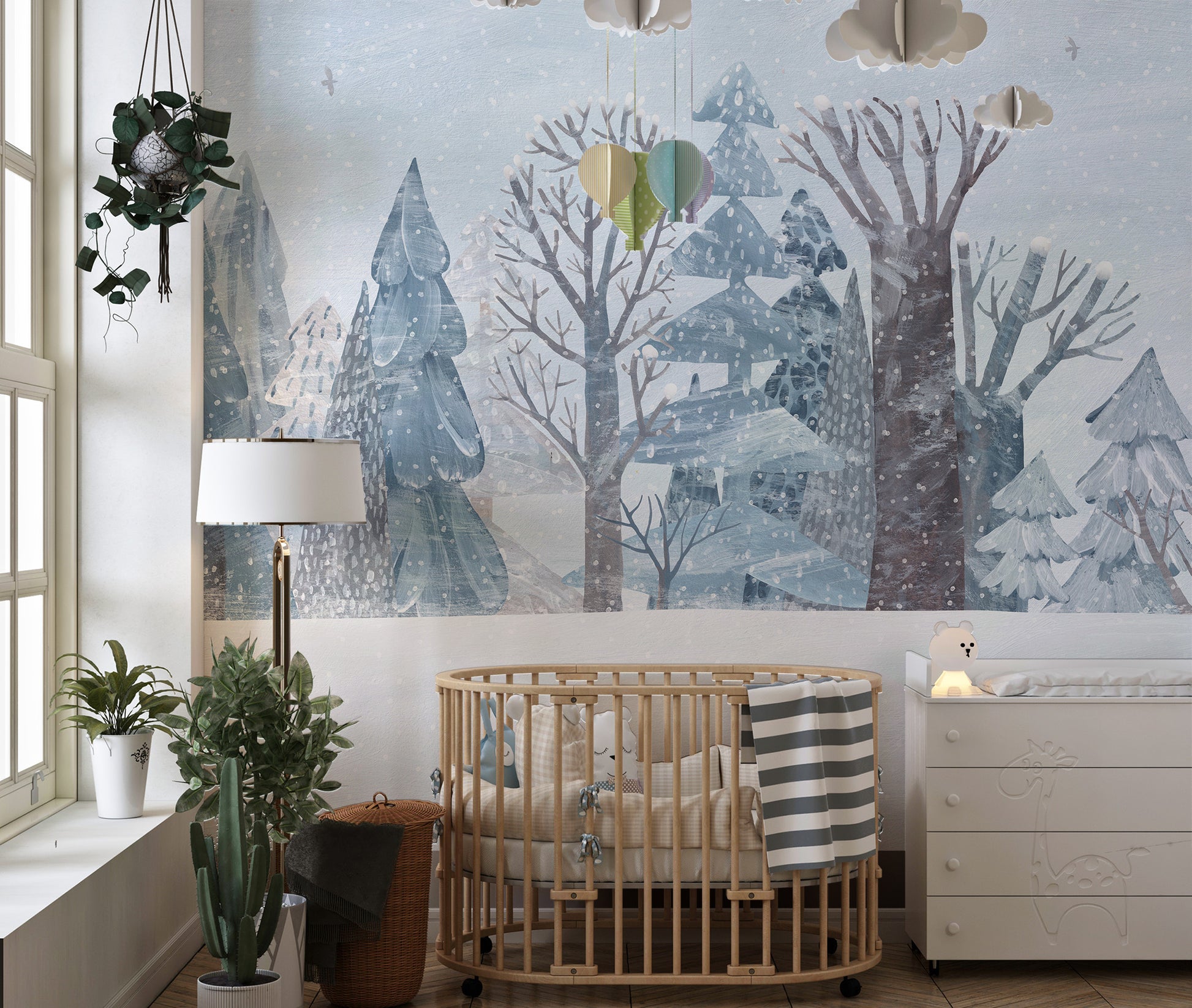 Winter Wonderland Forest wallpaper mural of snowy blue trees above a wood oval crib and white dresser in a nursery