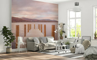 Piering into Nature's Heart wallpaper mural of a wooden pier on a pink lake behind a grey sofa in a bright living room