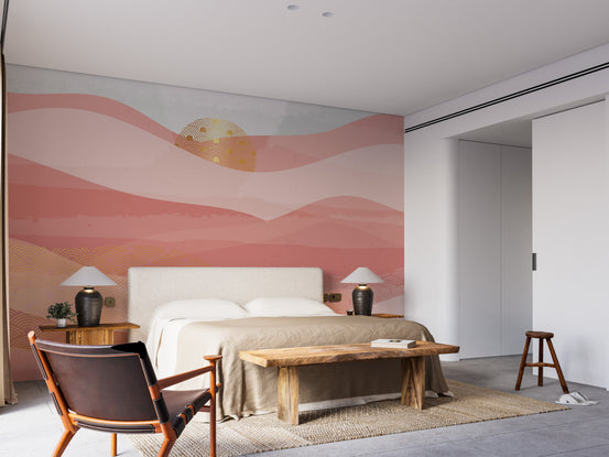 Pink Color Wavy Mountain wallpaper mural with golden sun behind a cream bed and wood bench in a bedroom