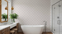 Pink Petal Lattice wallpaper behind a freestanding tub and marble vanity with gold pendants in a bathroom