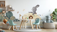Playful Bunny Car Ride Kids wallpaper mural in a playroom with a round table, teal chairs and stuffed animals