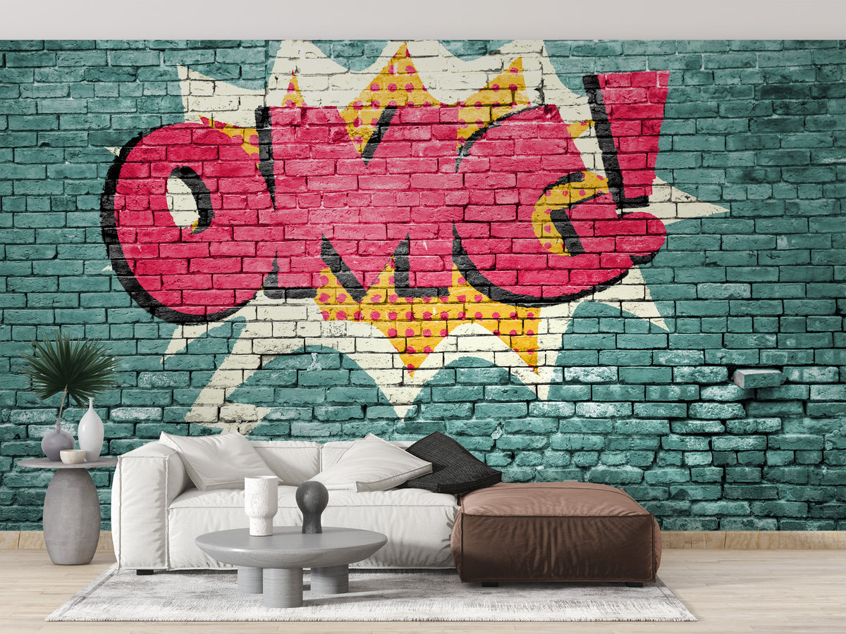 Pop Art OMG Graffiti wallpaper mural in red on a teal brick wall behind a white sofa and brown pouf in a living room