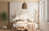 Soft Leaves wallpaper mural above a bed with peach bedding and rattan pendant light in a cozy bedroom