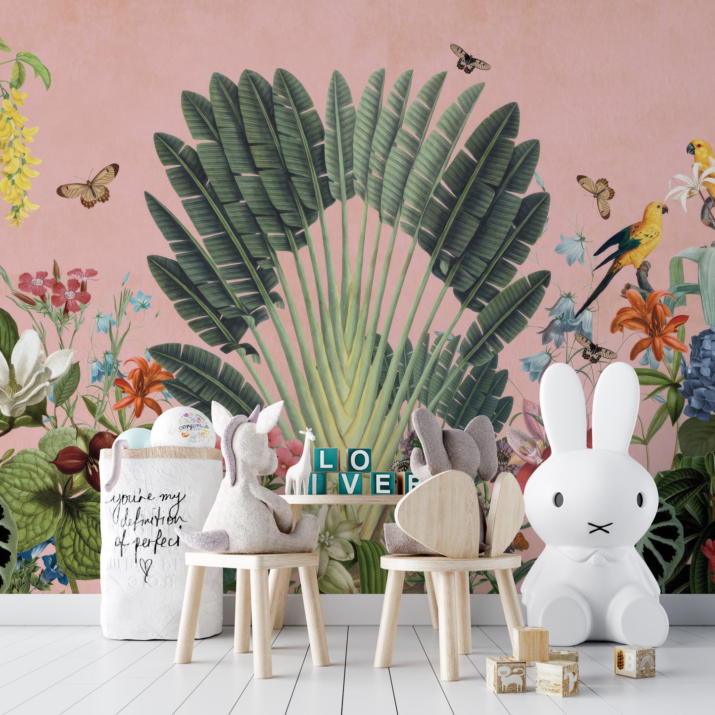 Sunbeam Canopy wallpaper mural of a banana palm fan and butterflies on pink behind bunny-shaped chairs and a white bunny lamp in a kids room
