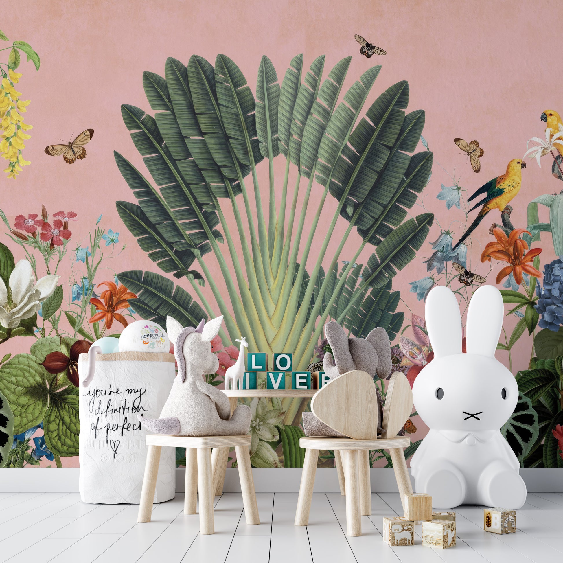 Sunbeam Canopy wallpaper mural of a banana palm fan and butterflies on pink behind bunny-shaped chairs and a white bunny lamp in a kids room