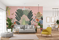 Sunbeam Canopy wallpaper mural with green palm fan and parrots on a pink wall behind a grey sofa and yellow armchair in a living room