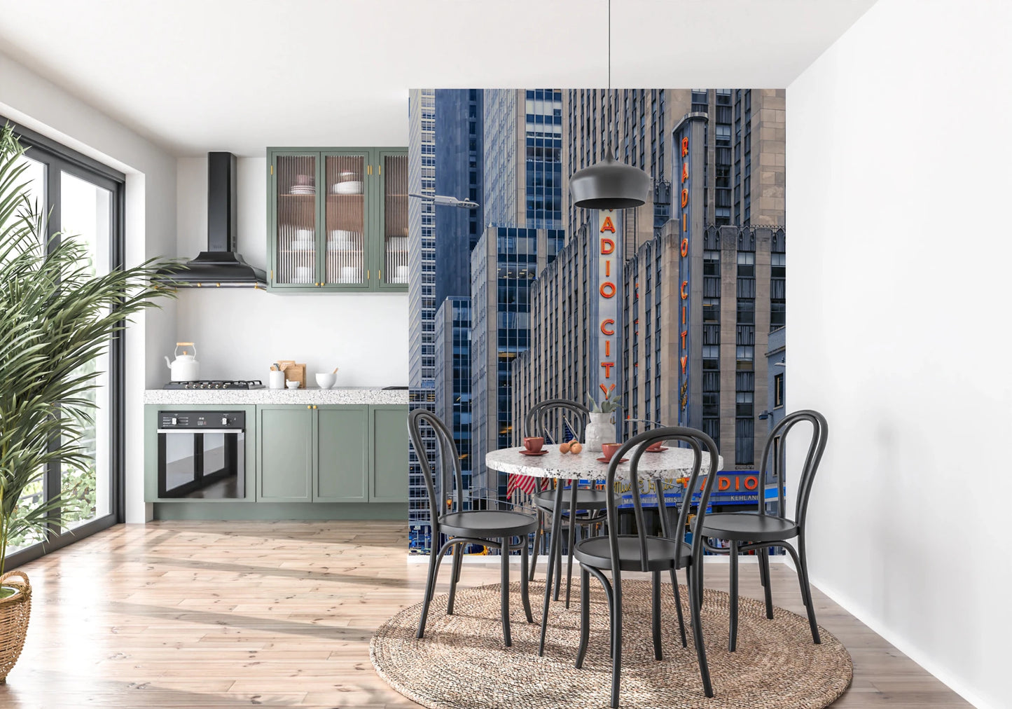 Radio City's Glow wallpaper mural of NYC towers beside a round terrazzo table in a sage green kitchen and dining nook