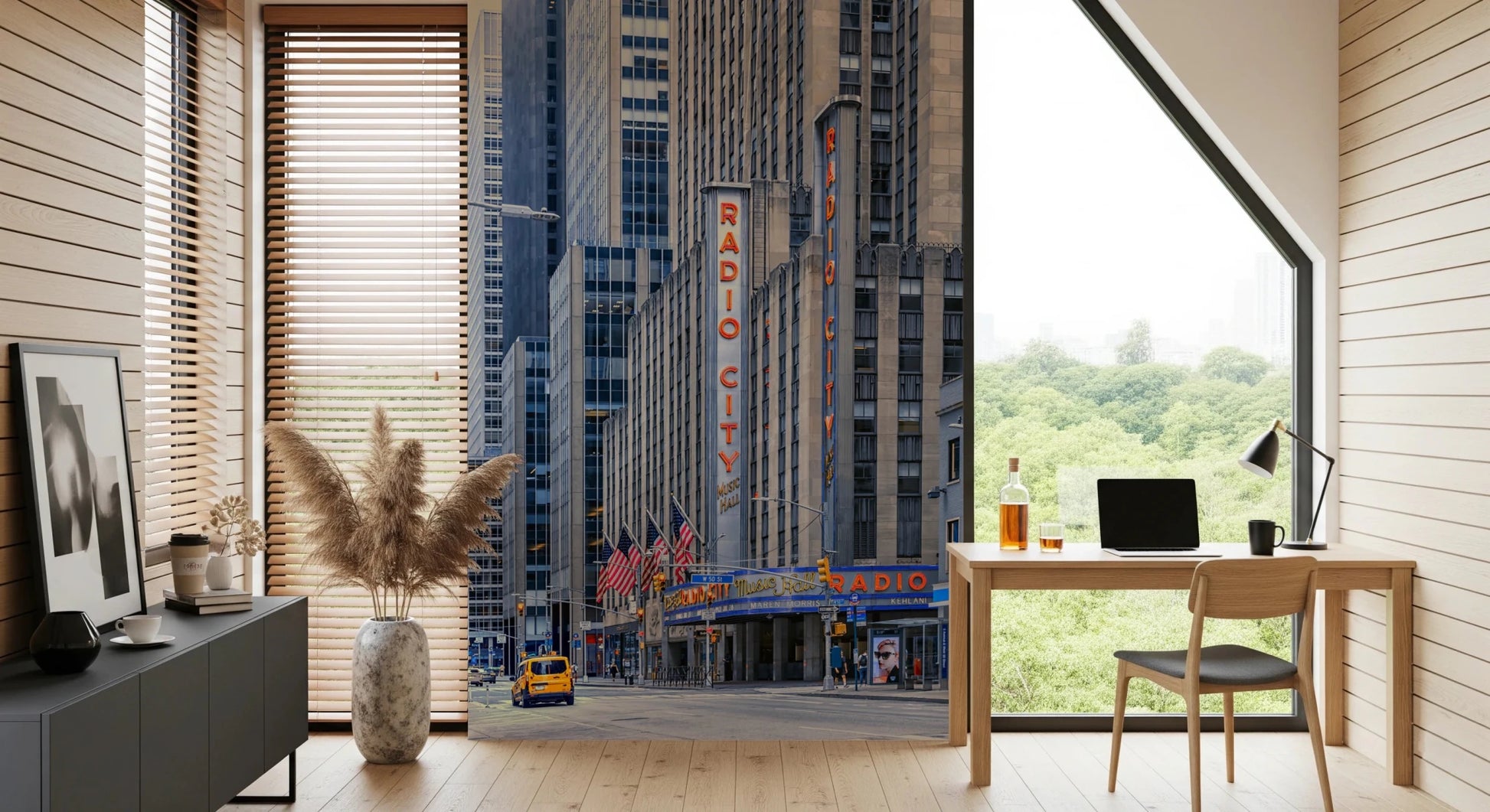 Radio City's Glow wallpaper mural of the Radio City sign behind a wood desk and laptop in a home office by a garden window