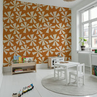 Geometric floral wallpaper with stylized star-like flowers across a warm orange background.