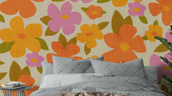 Retro Bright Flowers in Orange Pink Yellow wallpaper above a gray quilted bed in a close-up bedroom view