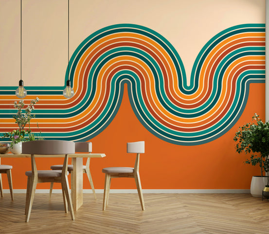 Retro Curvy Lines wallpaper mural in teal and orange waves behind a wood dining table and chairs with pendant lights