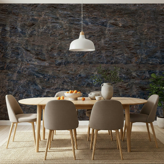 Rocky Terrain wallpaper mural in dark blue and brown stone behind an oval wood dining table with beige chairs